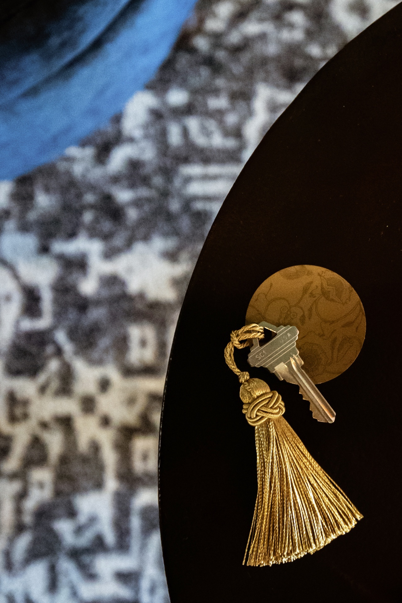 Room key and tassel resting on a dark table