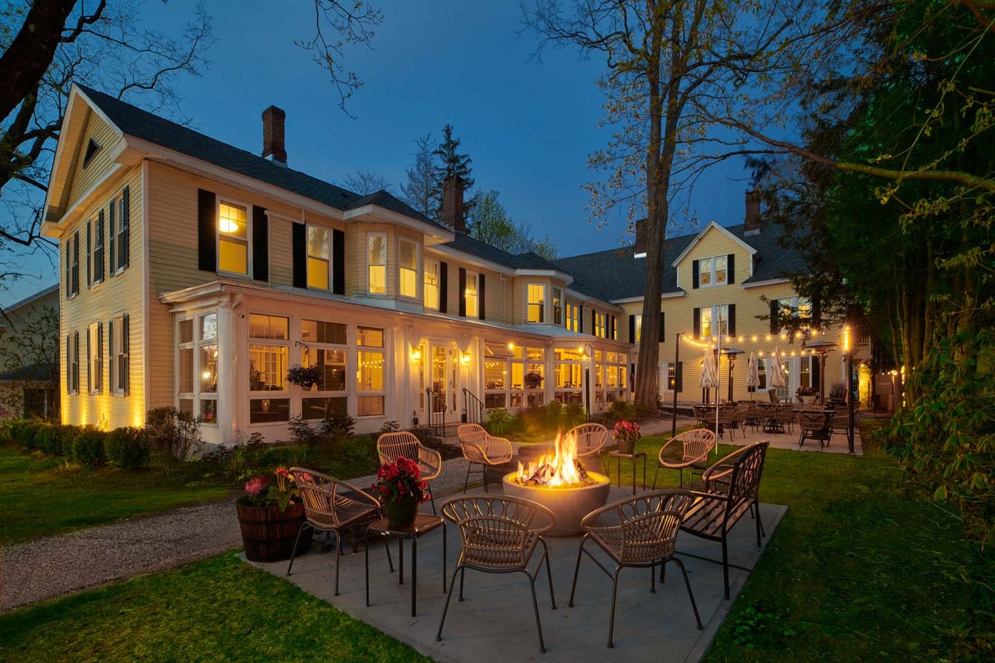 Inn exterior glowing at blue hour with fire pit