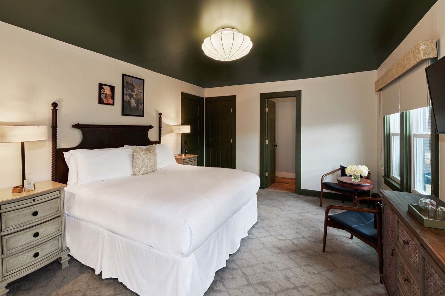 Guest room with carved dark headboard and green ceiling