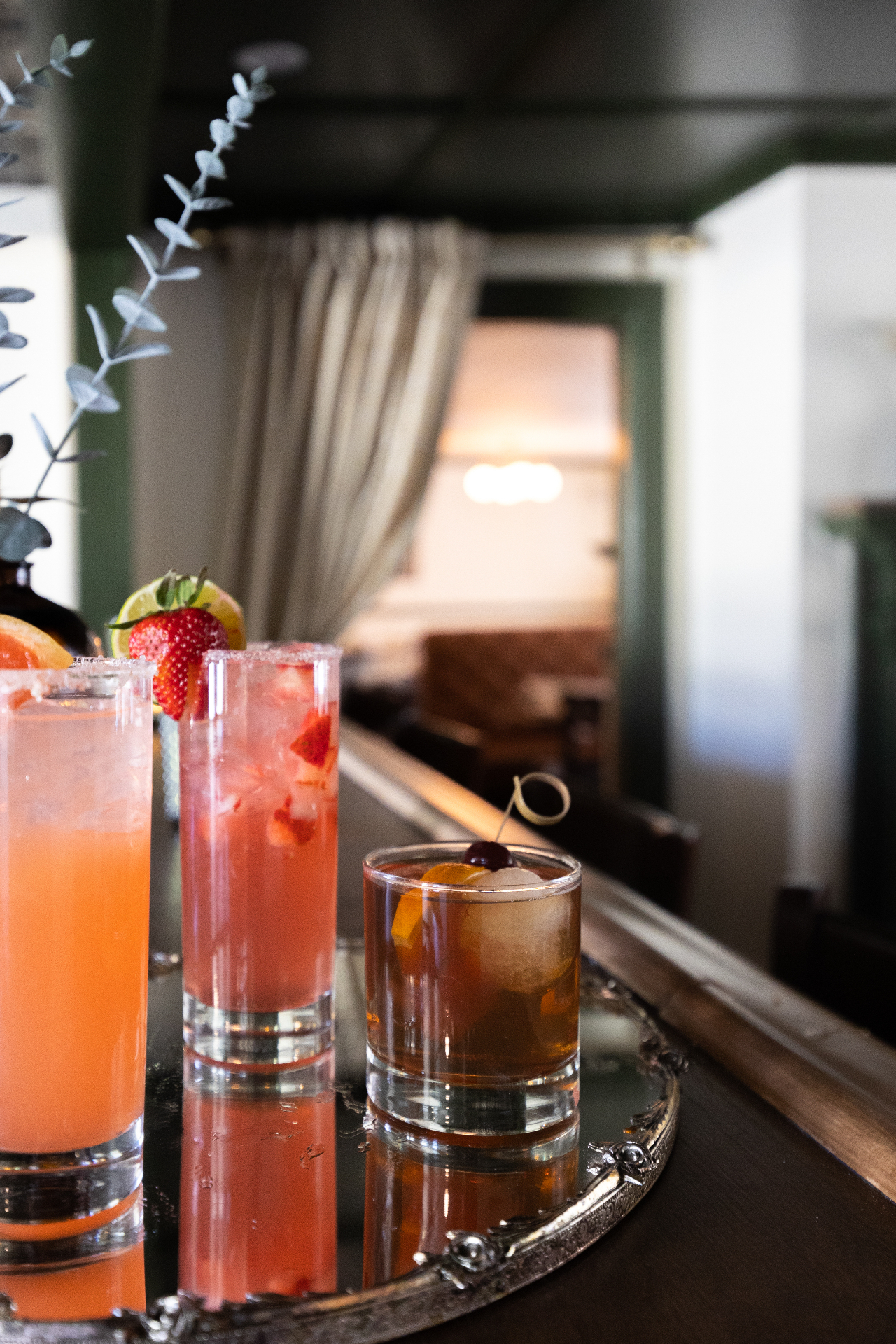 Three cocktails on a silver tray at the bar